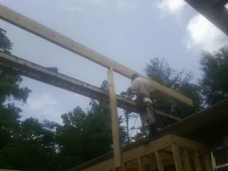 Carpenter setting a ridge beam over a new addition frame — Ice Dam Removal by Roofing Brothers in Chapin