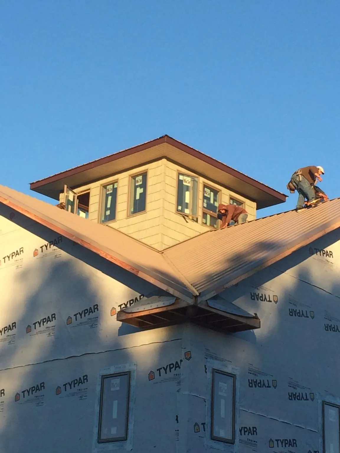 Roofers working around a rooftop cupola on a new metal roof at sunset — Roof Waterproofing in Chapin by Roofing Brothers